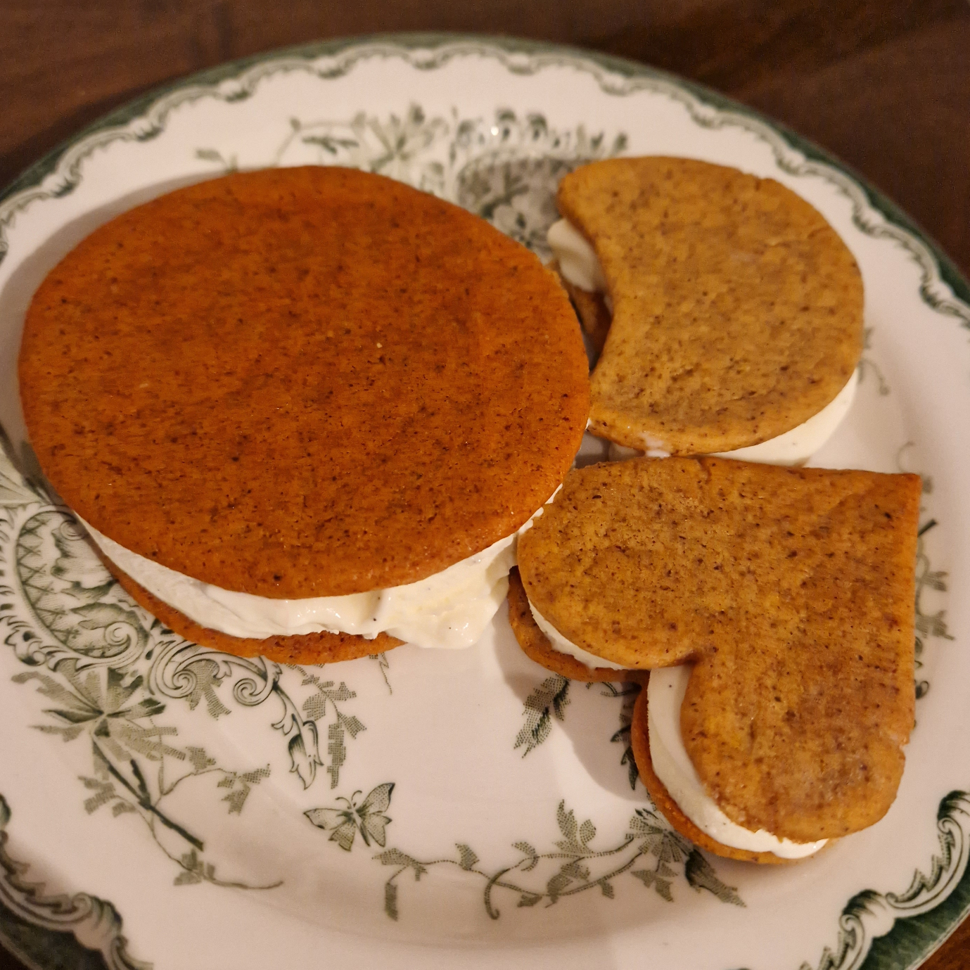 Three ice cream sandwiches. One is a circle, one is a moon, one is a heart. They're on a plate.