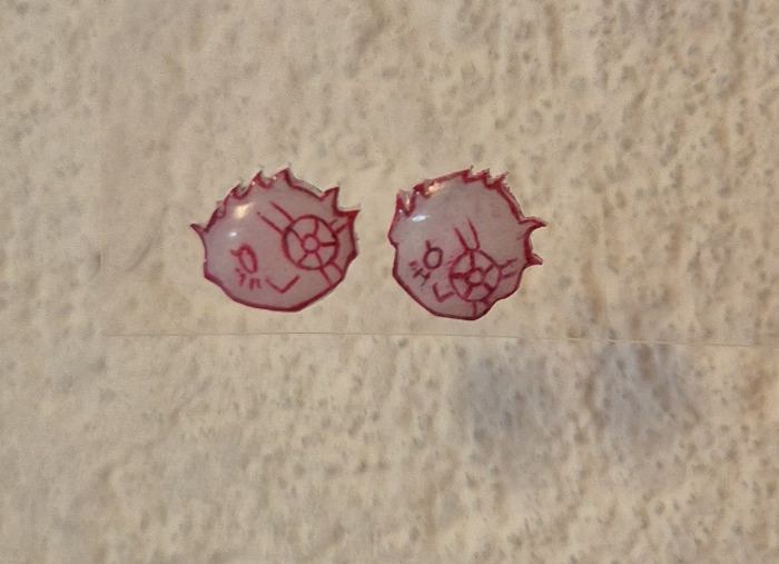 Stud earrings of a little chibi anime head of a character with an eyepatch, smiling